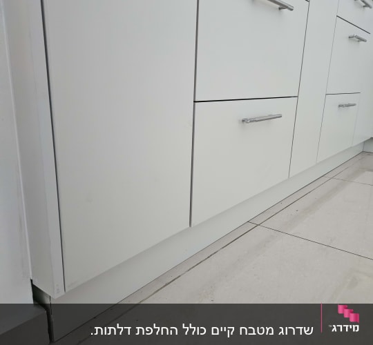 ארונות מטבח לבנים עם ידיות מתכת על רצפה בהירה